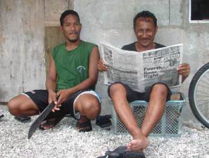 Rivel Line sits with Brian Tabto, who is enjoying reading the Marshall Islands Journal.