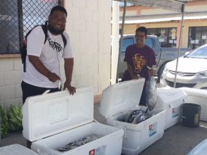 Nibaan Edwin and Austin August show the size range of fish at MISCO Market. Photo: Karen Earnshaw