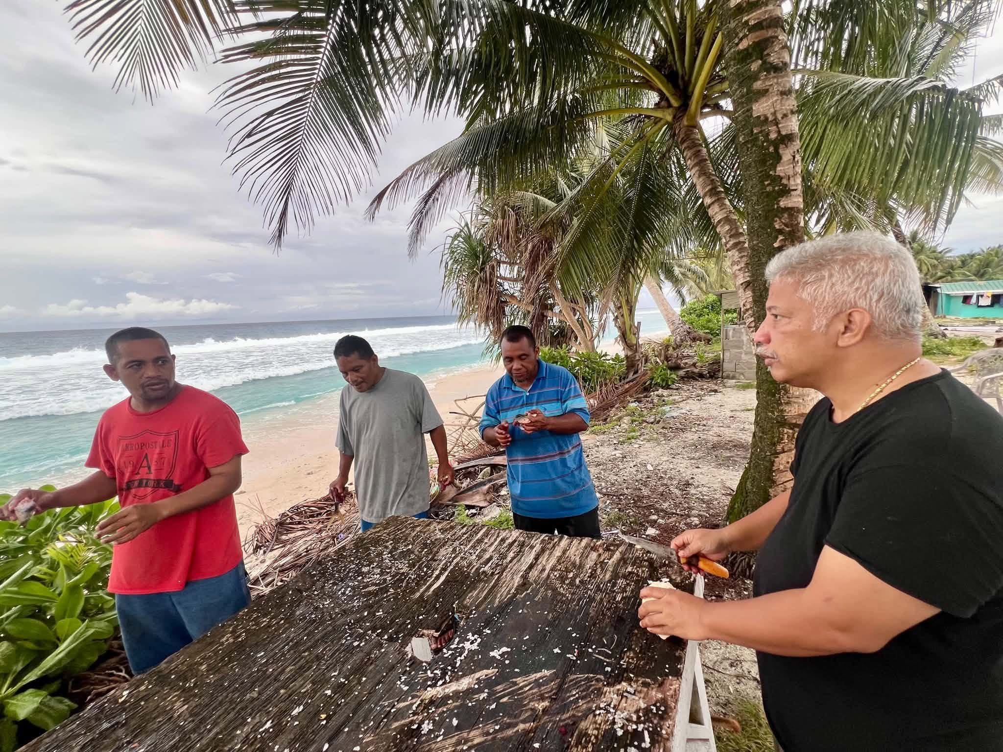 Kili Island, Christmas 2025 — cracking coconuts at a beachside table