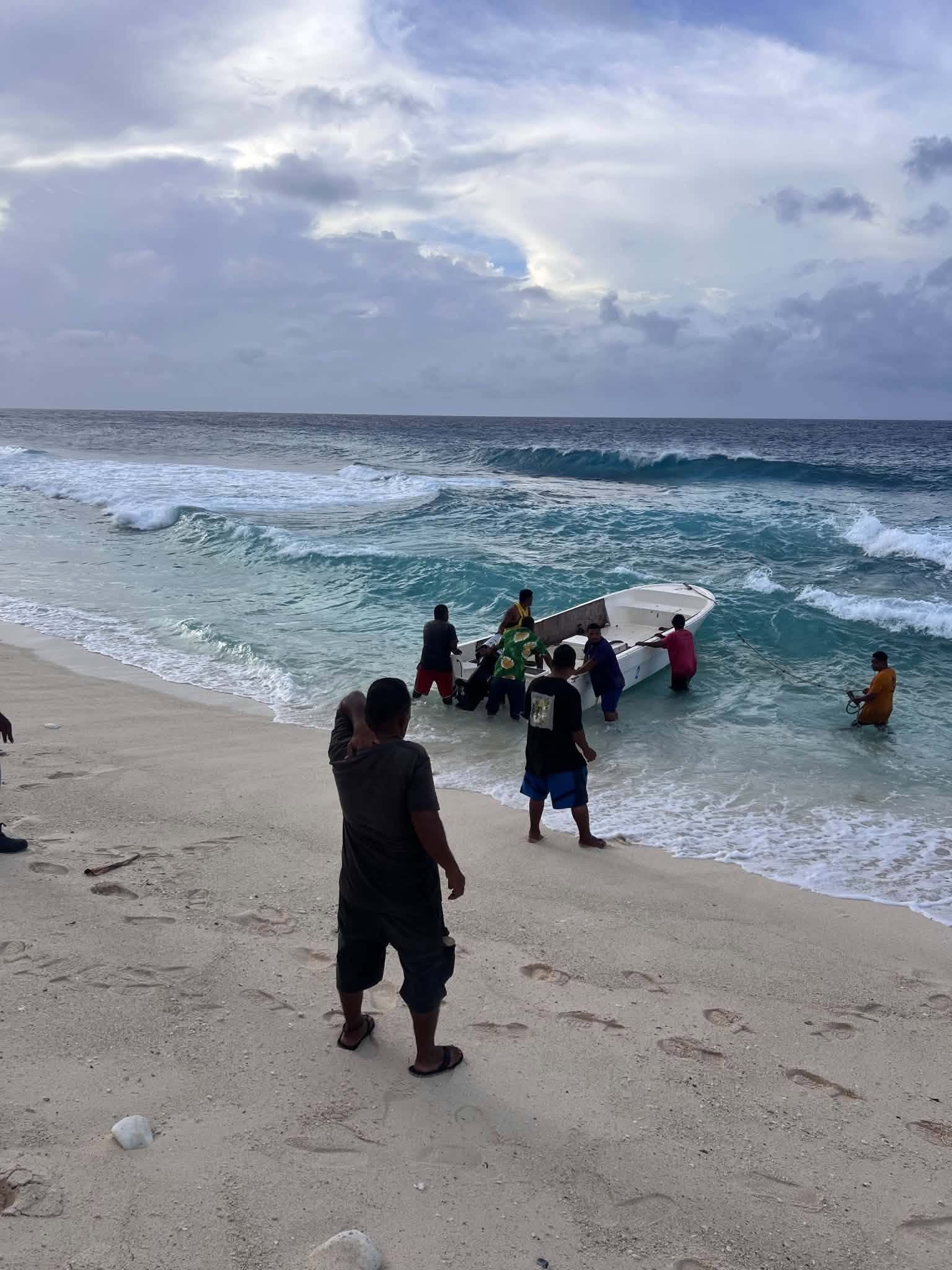 Kili Island, Christmas 2025 — a group gathers around a boat at the water's edge