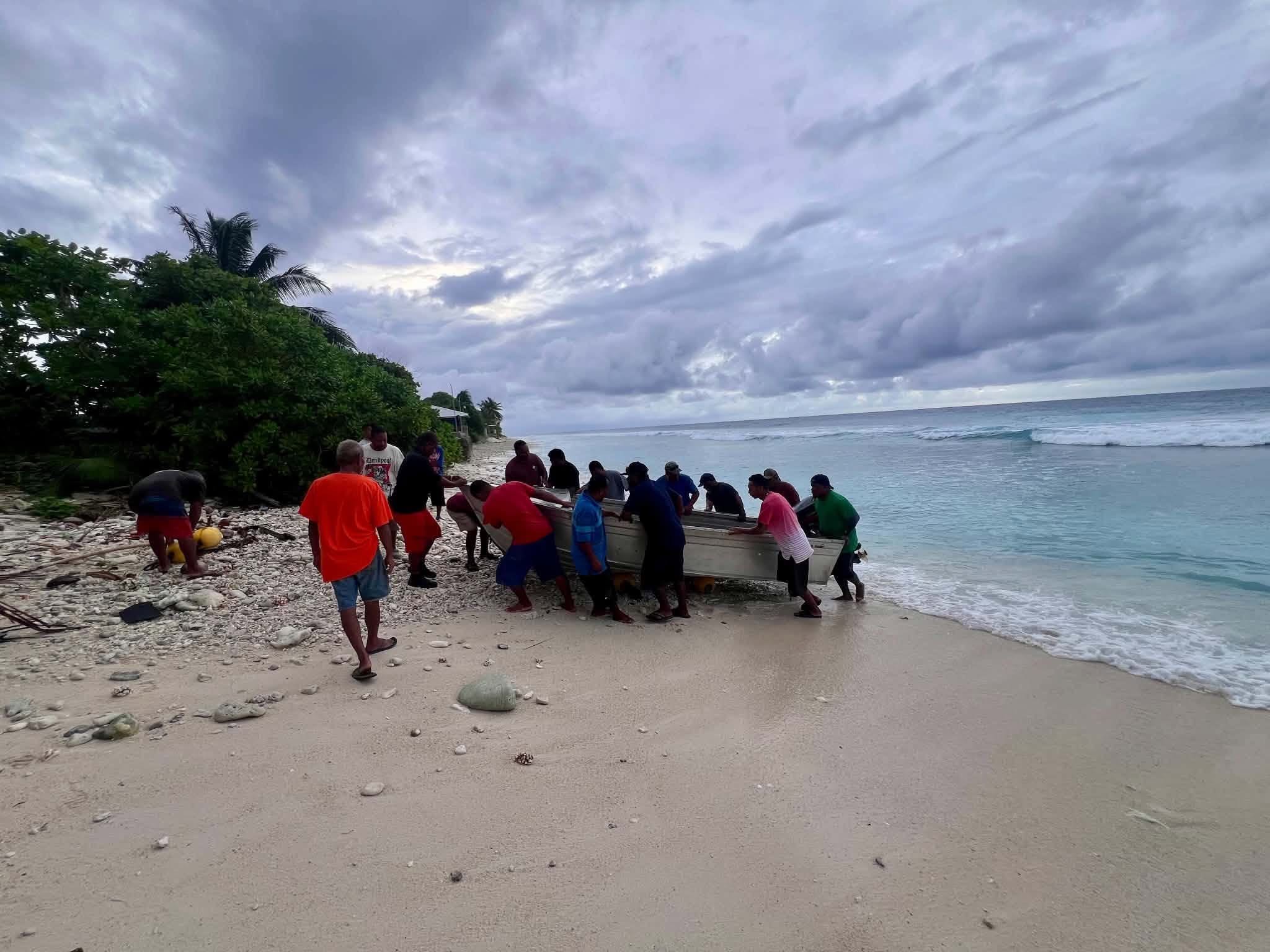 Kili Island, Christmas 2025 — a group hauling a boat up the beach