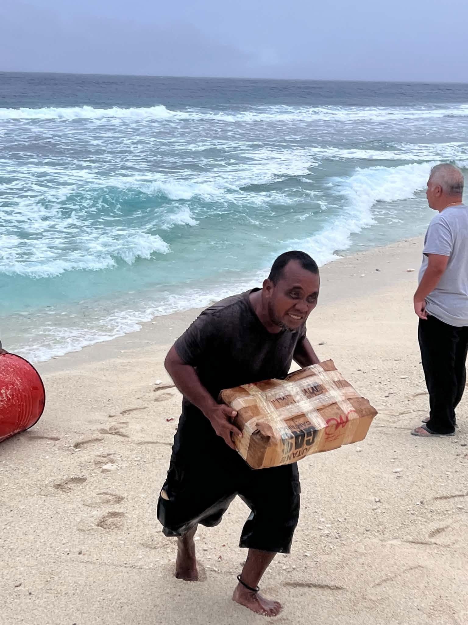 Kili Island, Christmas 2025 — a man carrying a wrapped package up the beach