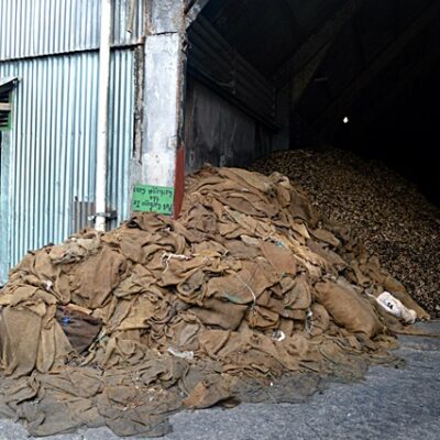 Copra sacks 'seep' out of the huge storage area at the Tobolar copra processing plant. Photo: Karen Earnshaw