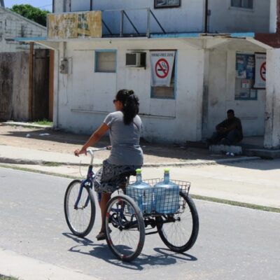 A woman carries precious water on the back of her bicycle. Photo: Westward II
