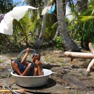 A young boy in Enejelar village on Ailuk uses the waste water from a watermaker to have a bath.