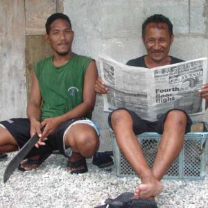 Rivel Line sits with Brian Tabto, who is enjoying reading the Marshall Islands Journal.