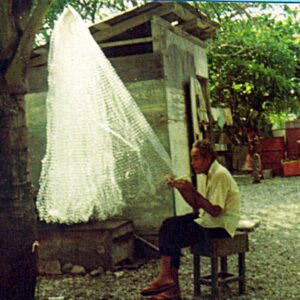 An unknown man repairs his fishing net.